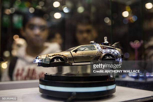 Visitors look at a hovering DeLorean DMC-12 figurine, from the "Back To The Future" movie trilogy, displayed at the "Toy Soul 2015" exhibition in...