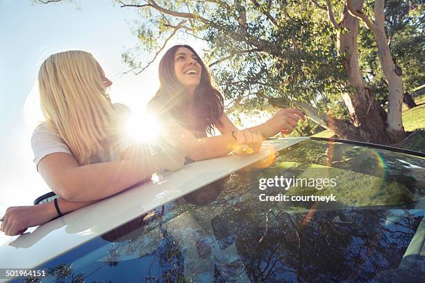 zwei junge frauen schiefer aus dem sonnendach-hintergrundbeleuchtung von der sonne - sun flare couple stock-fotos und bilder