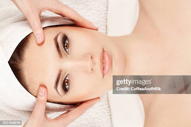 young woman doing facial massage - facial massage stock pictures, royalty-free photos & images