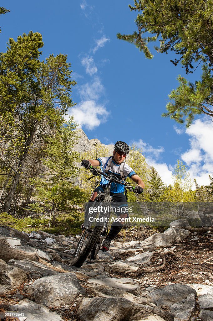 Mountain biker descends steep rocky trail, mtns