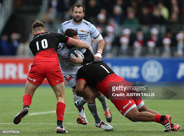 Oyonnax's full back from France Florian Denos is tackled by Saracens' fly-half from England Owen Farrell and Saracens' prop from England Mako...