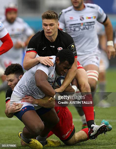 Oyonnax's centre from Fiji Uwanakaro Tawalo is tackled by Saracens' centre from Scotland Duncan Taylor and Saracens' fly-half from England Owen...