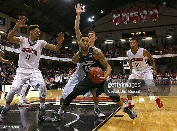 Denzel Valentine of the Michigan State Spartans is defended by Jeremy Miller and T.J. Williams of the Northeastern Huskies in the first half on...