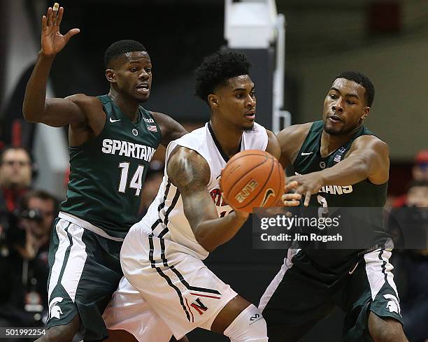 Quincy Ford of the Northeastern Huskies is defended by Eron Harris and Javon Bess of the Michigan State Spartans in the first half on December 19,...