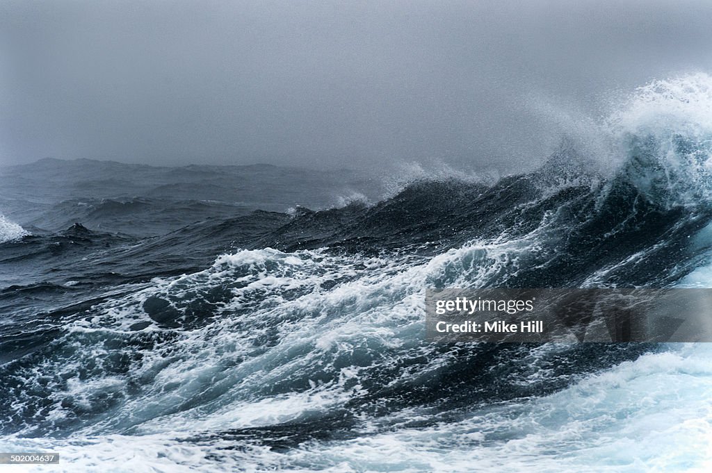 Breaking wave on a rough sea against overcast sky