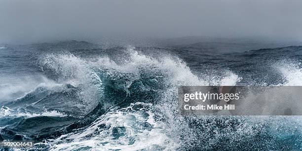 breaking wave on a rough sea against overcast sky - burrasca fotografías e imágenes de stock