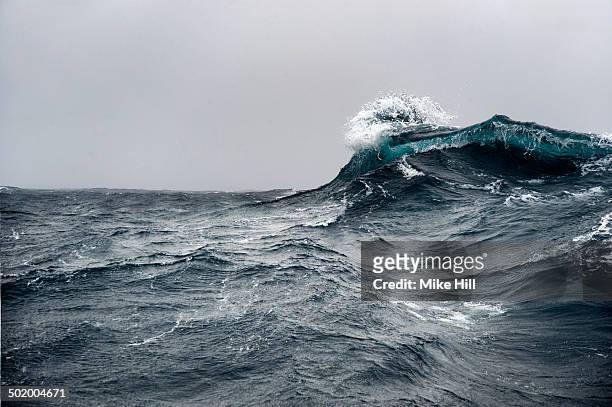 breaking wave on a rough sea against overcast sky - ruffled imagens e fotografias de stock