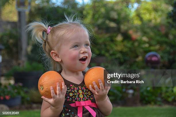 smiling 1 1/2 year old girl holding grapefruits - 12 year old blonde girl ストックフォトと画像