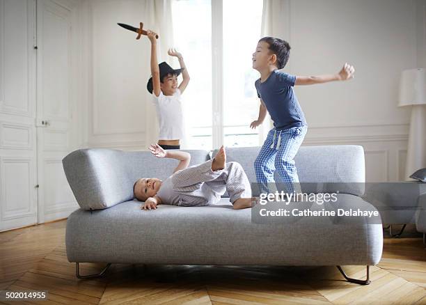 3 brothers playing in the living room - playing sofa stock-fotos und bilder