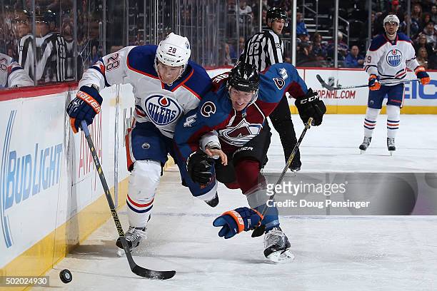 Lauri Korpikoski of the Edmonton Oilers and Tyson Barrie of the Colorado Avalanche pursue the puck at Pepsi Center on December 19, 2015 in Denver,...