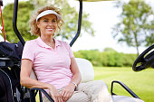 Mature woman sitting in a golf cart smiling