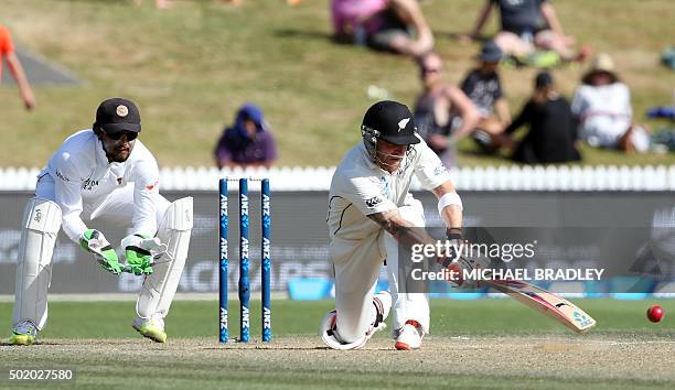 Brendon McCullum of New Zealand plays a shot as Dinesh Chandimal of Sri Lanka looks on, on day three of the second Test cricket match between New...