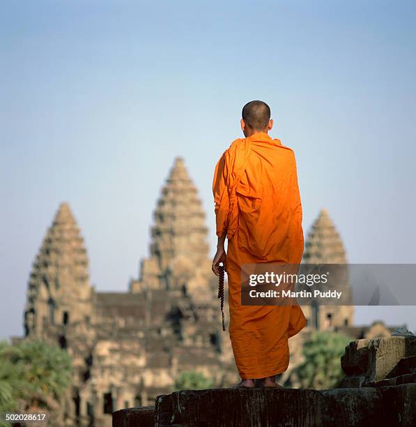 buddhist monk standing in front of angkor wat - cambodge photos et images de collection