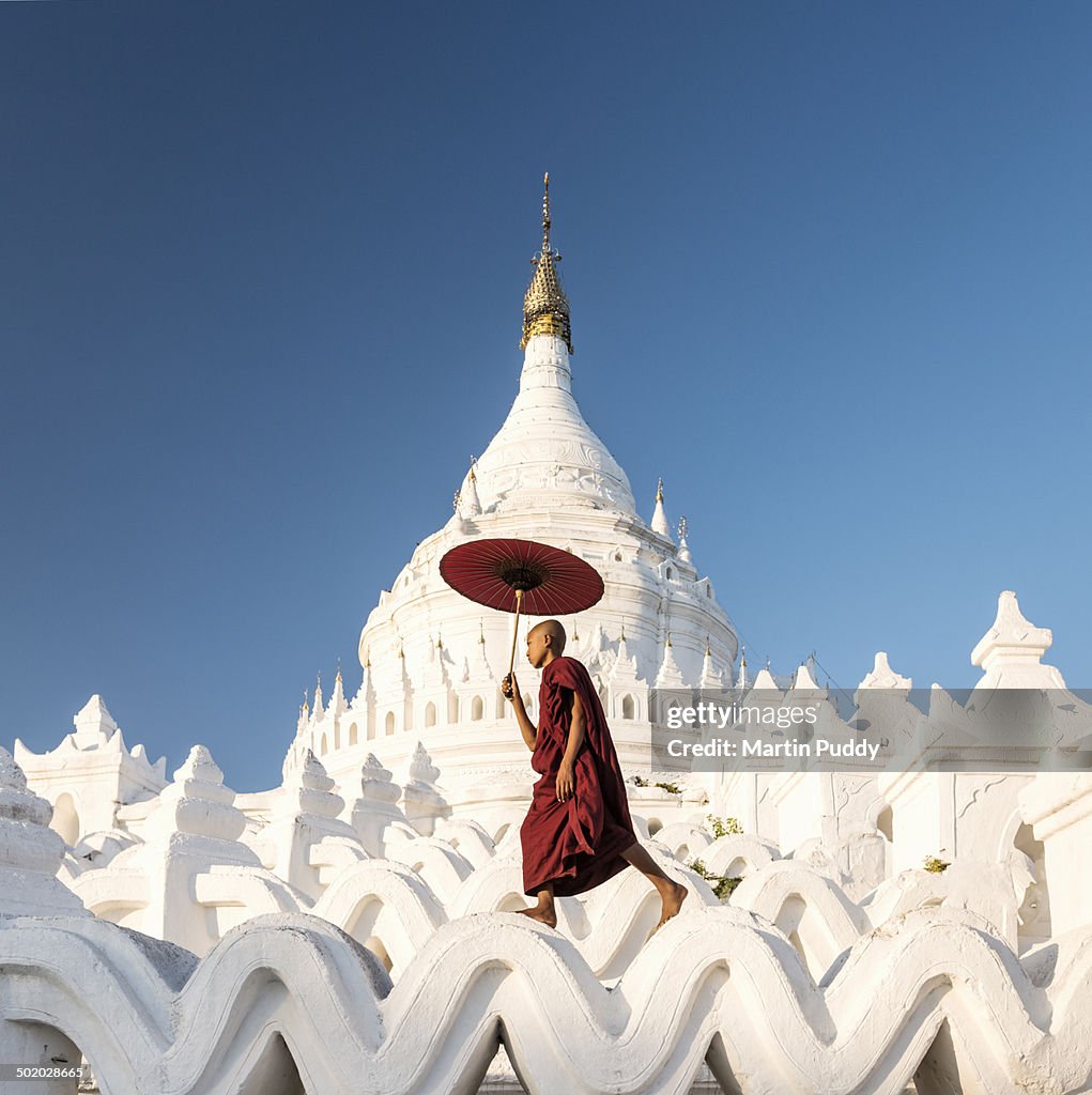 Buddhist monk walking across arches of temple