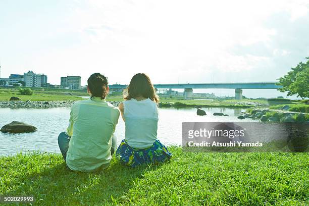 rear view of young couple beside river - 河川敷 ストック��フォトと画像