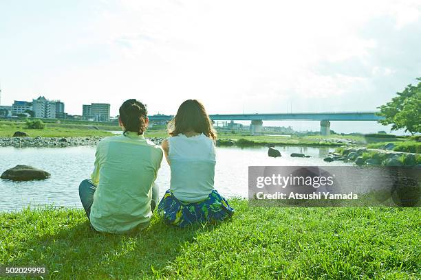 rear view of young couple beside river - riverside stock pictures, royalty-free photos & images