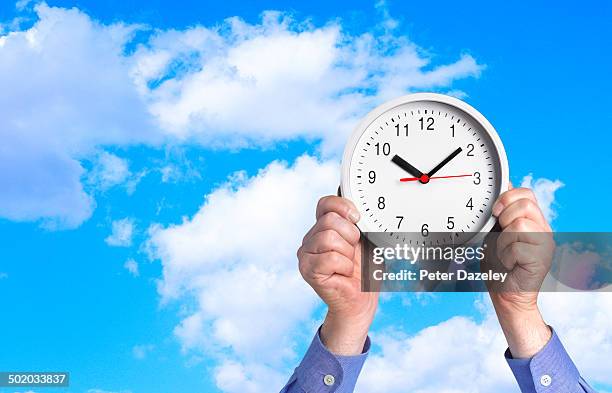 man holding up clock against sky - arm span stockfoto's en -beelden