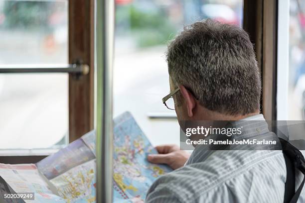 man looking at map while riding public transportation - vouyer stock pictures, royalty-free photos & images