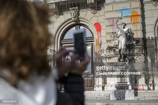Woman snaps a picture of the "Grand Theatre de Geneve" opera house on December 20, 2015 in Geneva, after it was vandalised during a demonstration the...