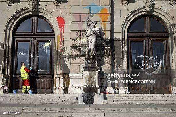Cleaner wipes a window of the "Grand Theatre de Geneve" opera house on December 20, 2015 in Geneva, after it was vandalised during a demonstration...