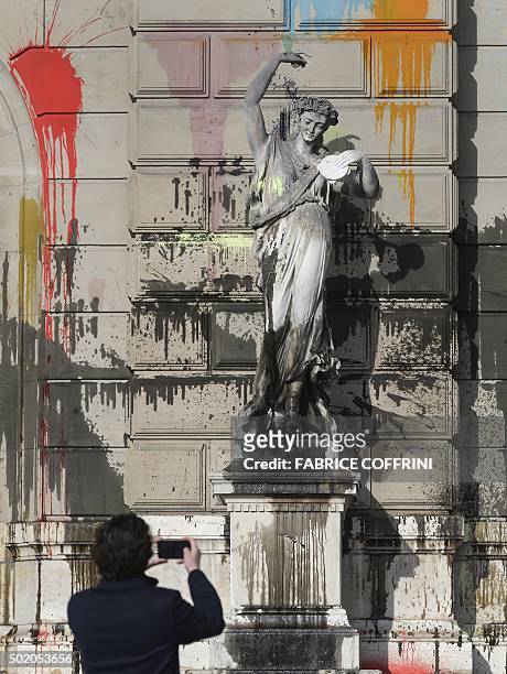 Man takes a picture of a statue outside the "Grand Theatre de Geneve" opera house on December 20, 2015 in Geneva, after it was vandalised during a...