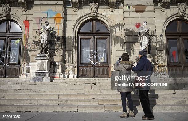 Woman takes a picture of a statue outside the "Grand Theatre de Geneve" opera house on December 20, 2015 in Geneva, after it was vandalised during a...