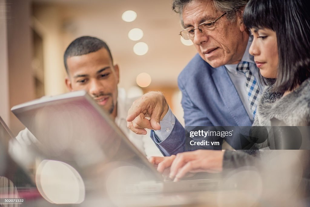Older man helping his younger colleagues in a relaxed environment