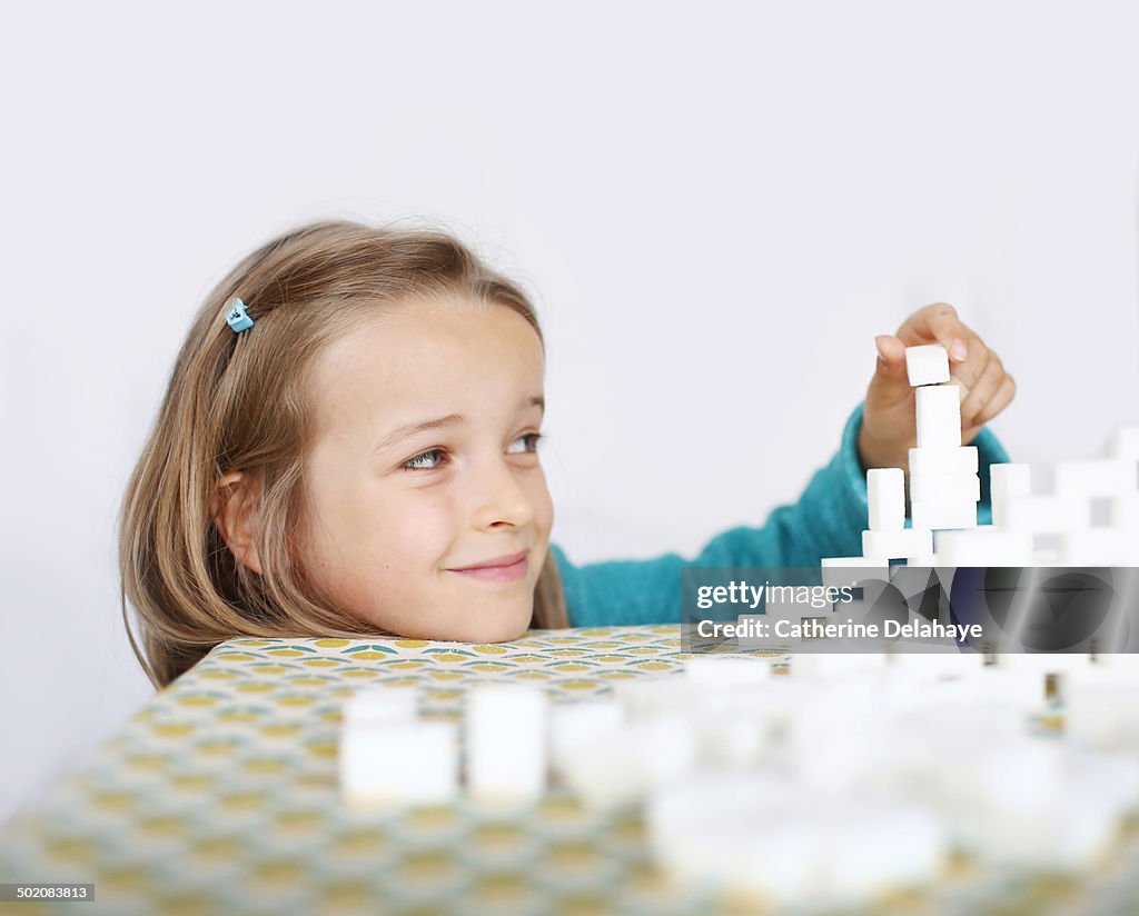 A 7 years old girl playing with sugar cubes