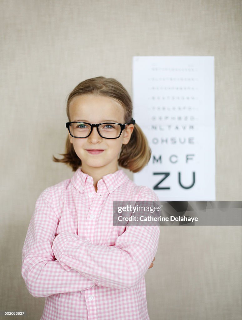 A 7 girl with glasses in front of a eye chart