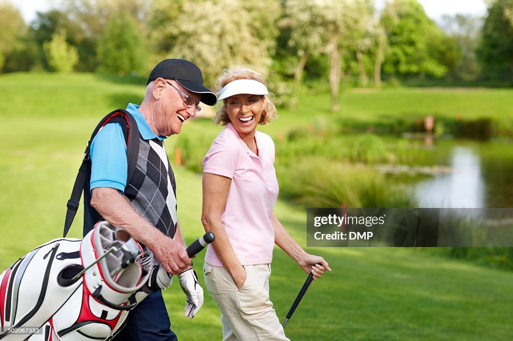 Cheerful mature couple walking on a golf course