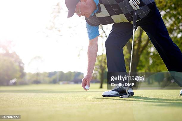 senior golfer taking ball out of the hole - golf short iron stock pictures, royalty-free photos & images