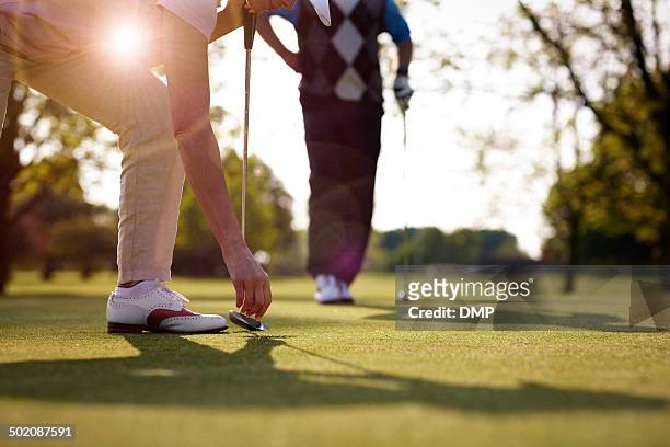 female golfer retrieving golf ball from hole - golf short iron stock pictures, royalty-free photos & images