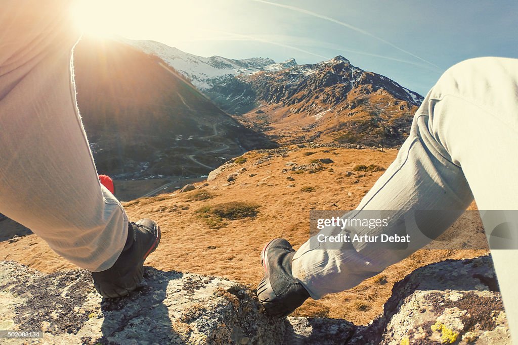 Man resting on top of rock in the Italian Alps with his legs from personal point of view.