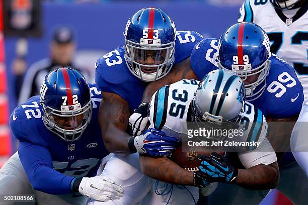 Mike Tolbert of the Carolina Panthers gets tackled by Kerry Wynn, Jasper Brinkley and Cullen Jenkins of the New York Giants in the first half during...