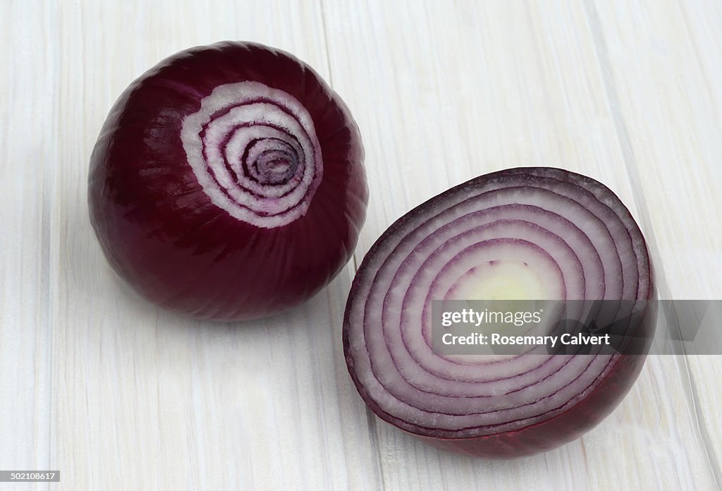 Half and whole red organic onion on white