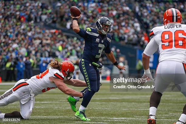 Quarterback Russell Wilson of the Seattle Seahawks passes under pressure from linebacker Paul Kruger of the Cleveland Browns at CenturyLink Field on...