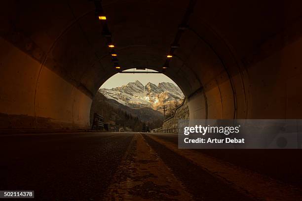 snowy alps view in the gran paradiso national park from inside the tunnel with nice frame. - dark country road stock pictures, royalty-free photos & images