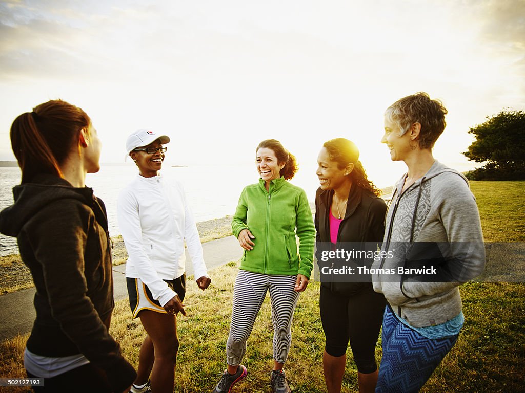 Female friends laughing together after run in park