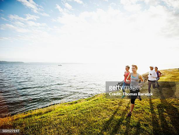 group of women running together on grass at sunset - day 4 stock-fotos und bilder