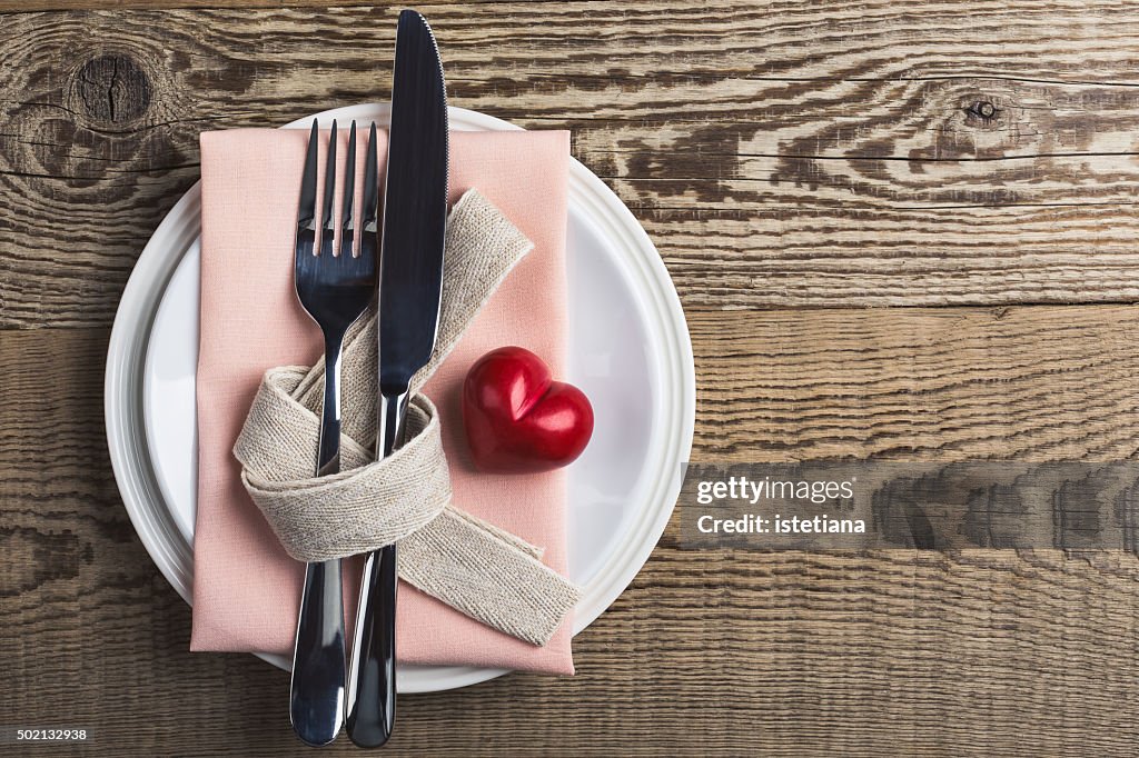 Valentines day table setting with knife, fork, ribbon and heart, top view