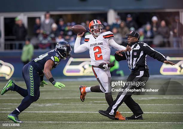 Quarterback Johnny Manziel of the Cleveland Browns passes the ball as he runs into umpire Barry Anderson, right, while linebacker Bobby Wagner of the...