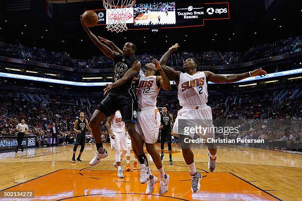 Khris Middleton of the Milwaukee Bucks lays up a shot past T.J. Warren and Eric Bledsoe of the Phoenix Suns during the second half of the NBA game at...