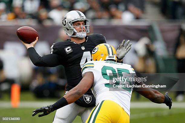 Quarterback Derek Carr of the Oakland Raiders passes under pressure from Defensive End Datone Jones of the Green Bay Packers in the first quarter at...