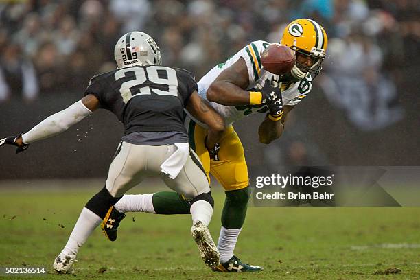 Wide receiver James Jones of the Green Bay Packers bobbles and pulls in a catch against cornerback David Amerson of the Oakland Raiders to set up his...