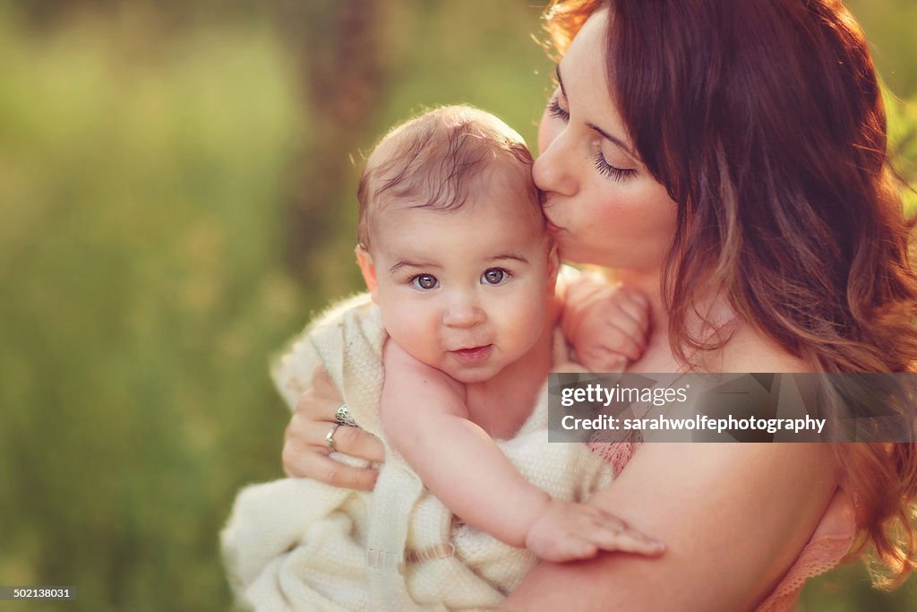 Beautiful woman kissing her baby's temple