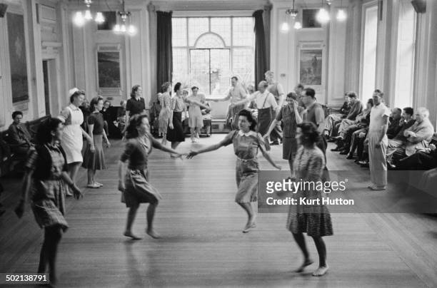 Patients participating in a therapeutic country dance session at a mental hospital in England, November 1946. Original publication: Picture Post -...