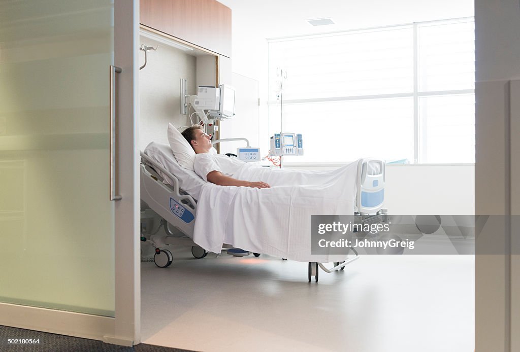 Männlichen Patienten im Krankenhaus liegen Bett und Ausblick durch die Tür. Sie trägt