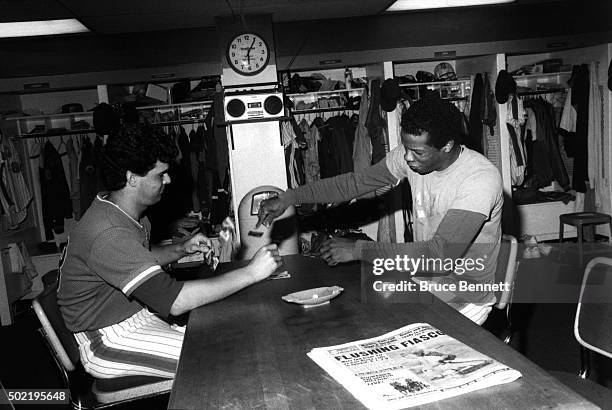 Pitchers Rick Aguilera and Dwight Gooden of the New York Mets play cards in the locker room before an MLB game circa 1985 at Shea Stadium in...