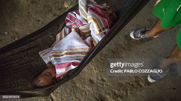 Waorani indigenous man watches a baby as he sleeps in Gareno, 175 km southeast of Quito, Ecuador on December 7, 2015. Three Amazonian ethnic groups...