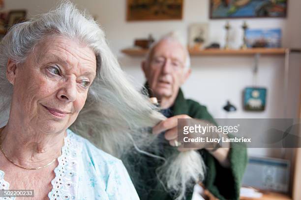 senior man brushing his wife's long grey hair - senior man grey long hair stock pictures, royalty-free photos & images